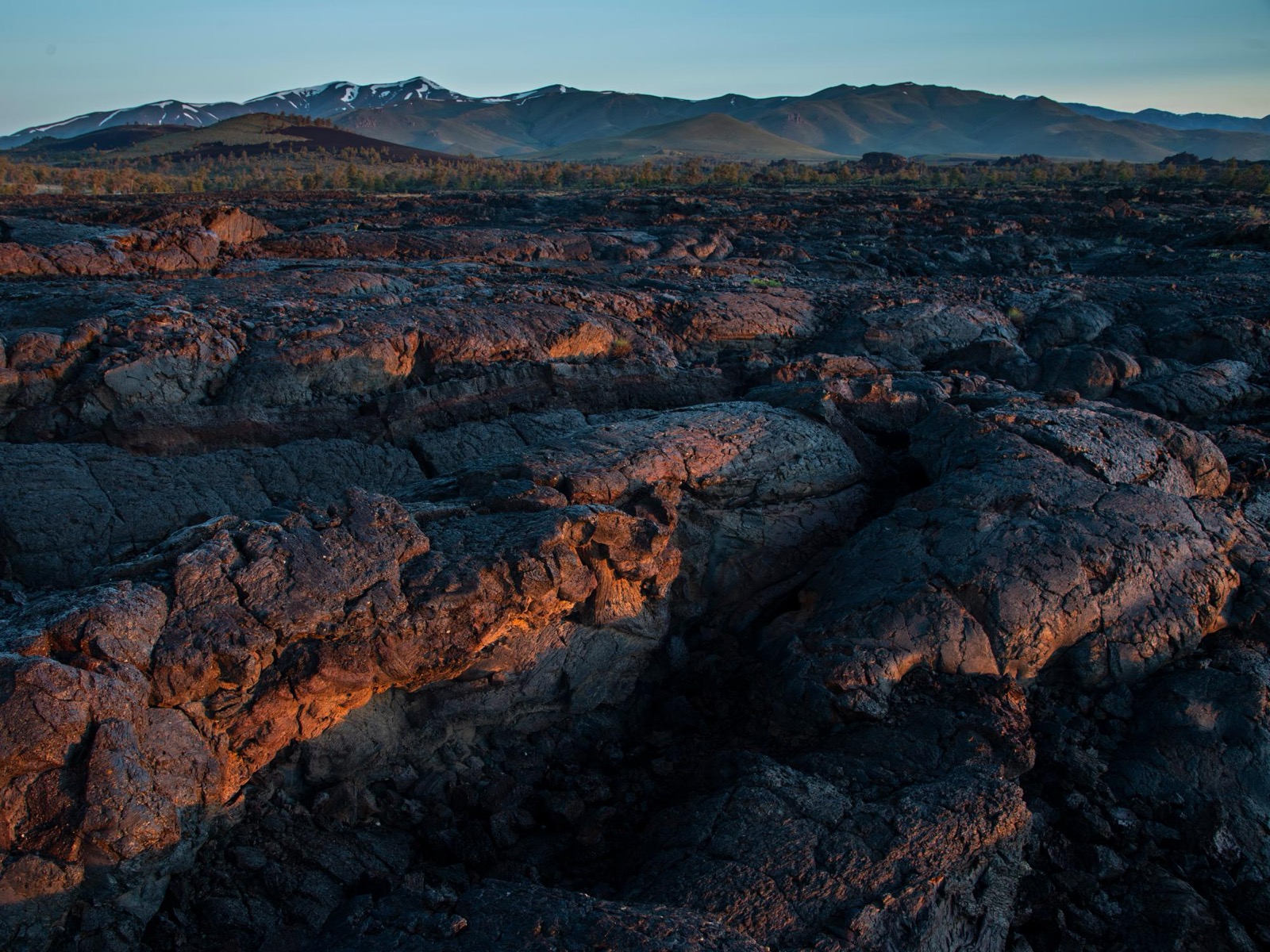 Dark volcanic lava fields and distant mountains at Craters of the Moon in Idaho